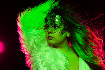 Close up portrait of curvy alternative model with colored hair and fur coat and fishnets under green and pink lighting