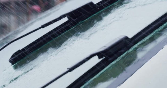 Super close up of a carglass while it&rsquo;s raining, the wipers are taking off the water from it. Concept: thunderstorm, car, weather. Shot on Red Camera 8K