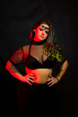 Curvy alternative model with colored hair and mesh clothing poses under red lighting