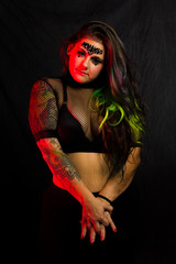 Curvy alternative model with colored hair and mesh clothing poses under red lighting