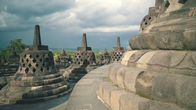 Stupas on top of Borobudur temple in Java, Indonesia on sunny evening, slide left