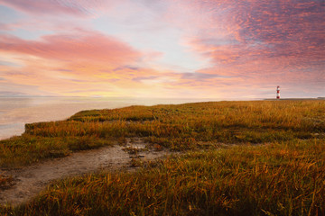 Colorful sunset on the sea with a lighthouse on the horizon