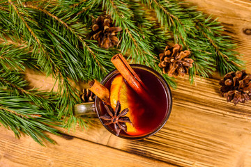 Cup of mulled wine with cinnamon and fir tree branches on wooden table. Top view