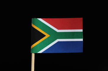 A national flag of South Africa on toothpick on black background. The flag has six colours yellow, white, red, blue, black, green.