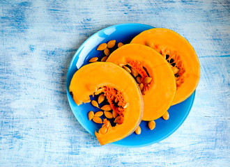 Three pieces of a pumpkin on a blue plate on a white-blue background