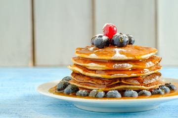 Stack of pancakes with fresh blueberries and maple syrup