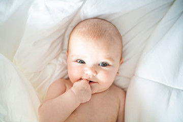 A Cute baby girl on a white bed at home