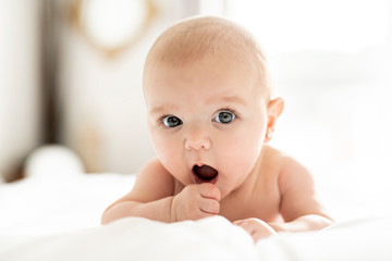 A Cute baby girl on a white bed at home yawn