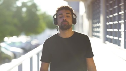 Millenial young man using his smartphone for listening music with headphones