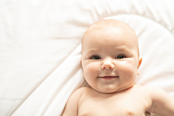 A Cute baby girl on a white bed at home