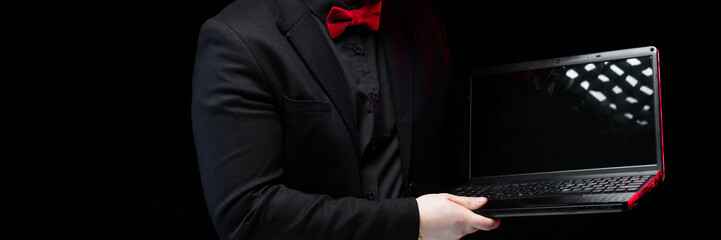 Portrait of confident handsome ambitious happy elegant responsible businessman working on his laptop on black background