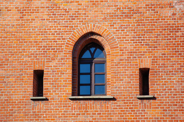 old weathered brick wall with windows in gothic style