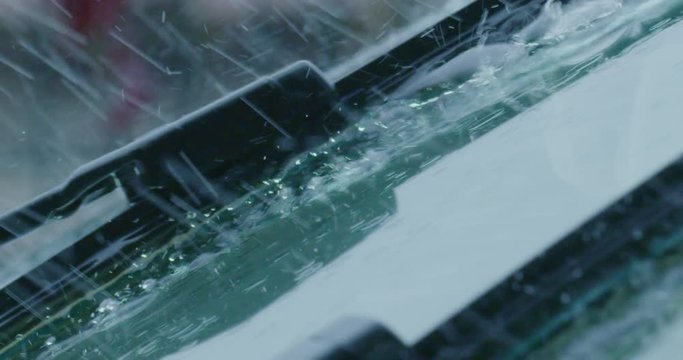 Super close up of a carglass while it&rsquo;s raining, the wipers are taking off the water from it. Concept: thunderstorm, car, weather. Shot on Red Camera 8K