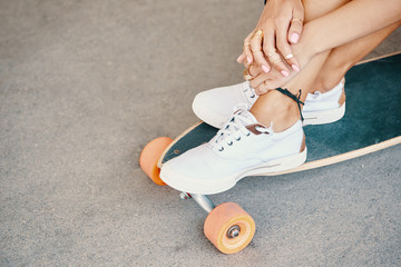 Woman in sneakers riding skateboard outdoor on asphalt surface.