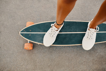 Woman in sneakers riding skateboard outdoor on asphalt surface. © arthurhidden