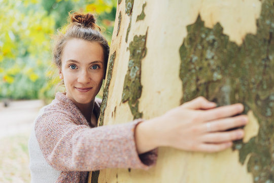 Pretty young woman hugging a tree trunk