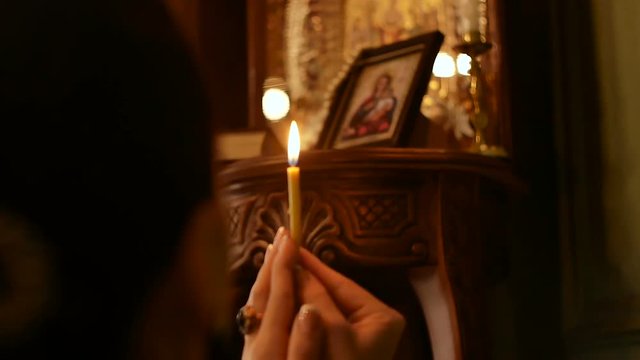 woman praying with a candle in her hands