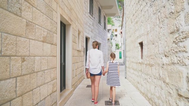 Mother with her daughter walking in the old town.