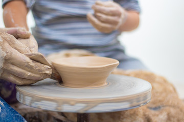 Ware from clay. The teacher helps the student to make clay dishes