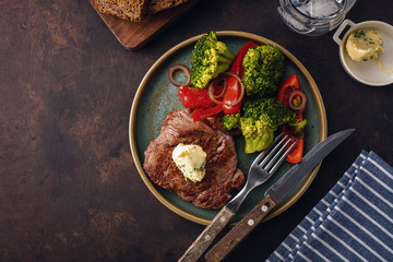 Grilled Beef steak with garlic butter and vegetables. Meat with grilled bell pepper, broccoli and onions.