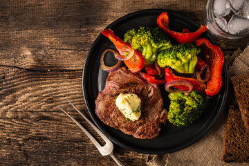 Grilled Beef steak with garlic butter and vegetables. Meat with grilled bell pepper, broccoli and onions.