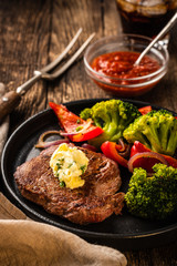 Grilled Beef steak with garlic butter and vegetables. Meat with grilled bell pepper, broccoli and onions.