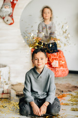 Little girl and boy sitting on the background of the moon and the baskets decorated under the new Year