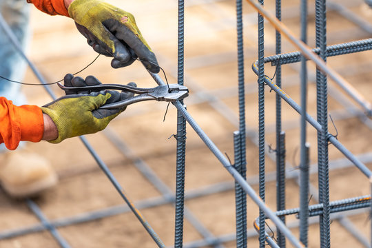 Worker Securing Steel Rebar Framing With Wire Plier Cutter Tool At Construction Site