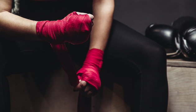Woman wraps her fists in pink bandages for boxing gloves