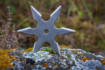 Shuriken (throwing star), traditional japanese ninja cold weapon stuck in wooden background