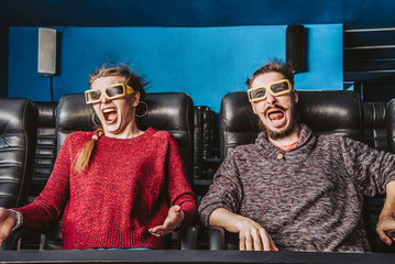 guy and girl 3d glasses are very worried while watching a movie in a cinema