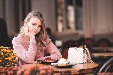 Smiling girl sitting in cafe with tasty breakfast. Looking at camera. 20s.