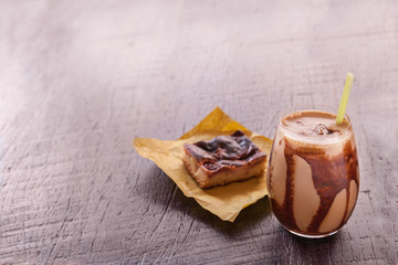 Ice coffee drink with chocolate syrup and strawberry cheesecake on the wood table. negative space