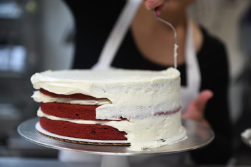 Woman frosting red velvet cake
