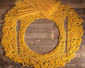 different kinds of pasta in circular layers in a old wood table