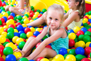 portrait of  girl playing in pool with plastic multicolored balls