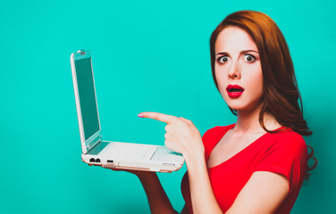 Redhead girl with laptop on blue background.