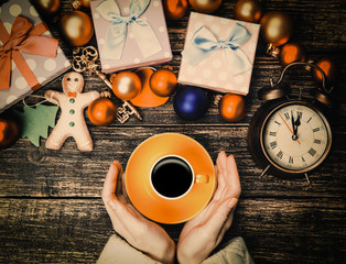 Female hands holding cup of coffee near christmas gifts on a table