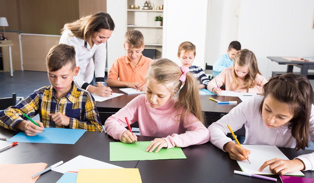 smiling little kids with teacher drawing in classroom