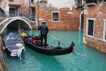 Fototapeta na wymiar Gondolier in a little canal of Venice