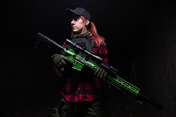 Woman with rifle in hands on dark background/Young girl with red hair holding a big rifle with an optical sight