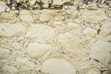 gray wall surface of old stones with plaster in cracks.