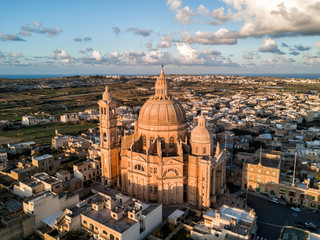 Aerial drone sunrise photo - Rotunda St. John Baptist Church in the town of Xewkija, Gozo.  Country of Malta.  Mediterranean Sea on the horizon