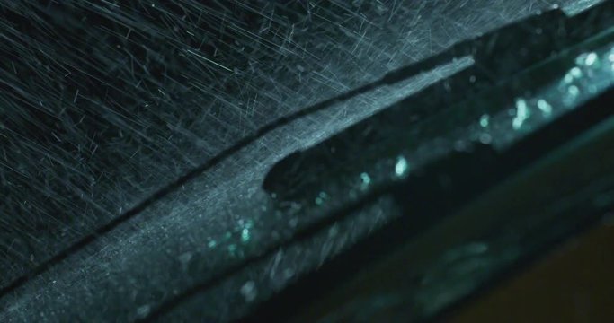 Super close up of a carglass while it&rsquo;s raining, the wipers are taking off the water from it. Concept: thunderstorm, car, weather. Shot on Red Camera 8K