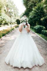 The bride covers her face with a beautiful bouquet