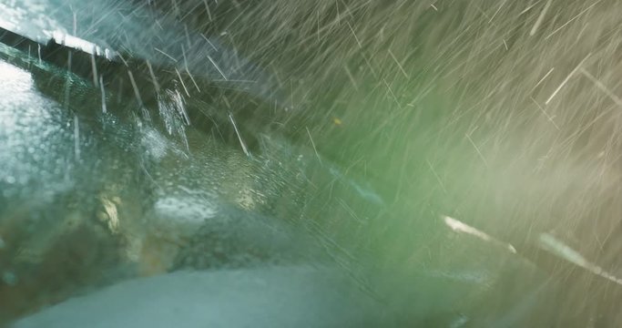 Super close up of a carglass while it&rsquo;s raining, the wipers are taking off the water from it. Concept: thunderstorm, car, weather. Shot on Red Camera 8K