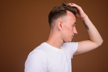 Young handsome man with blond hair against brown background