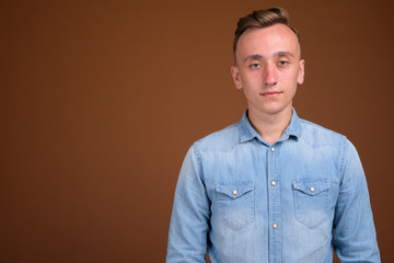Young handsome man with blond hair against brown background