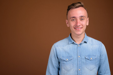 Young handsome man with blond hair against brown background