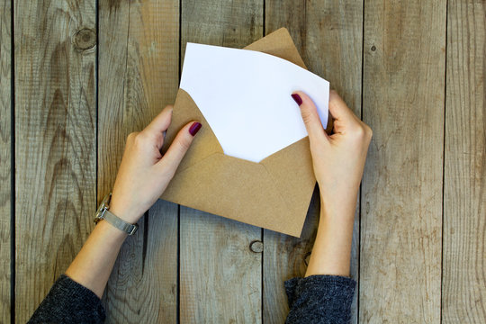 Woman Hand Opening Envelope On Wooden Table.